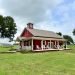 Red barn-style building with white accents surrounded by greenery.